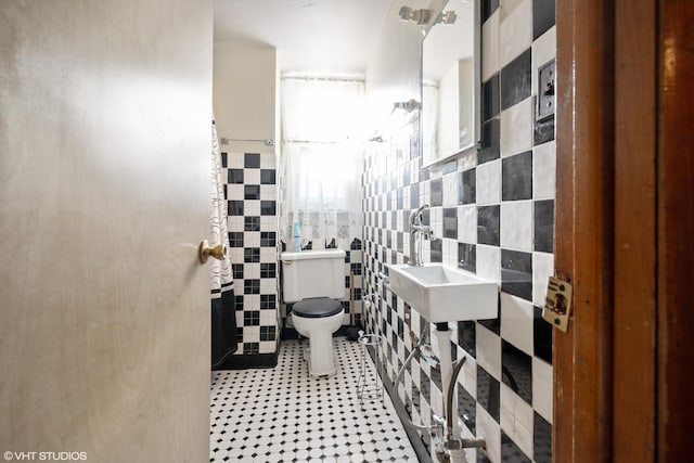 bathroom with sink, tile walls, and toilet