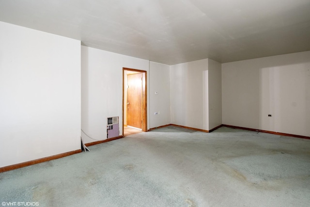 unfurnished room featuring heating unit and light colored carpet