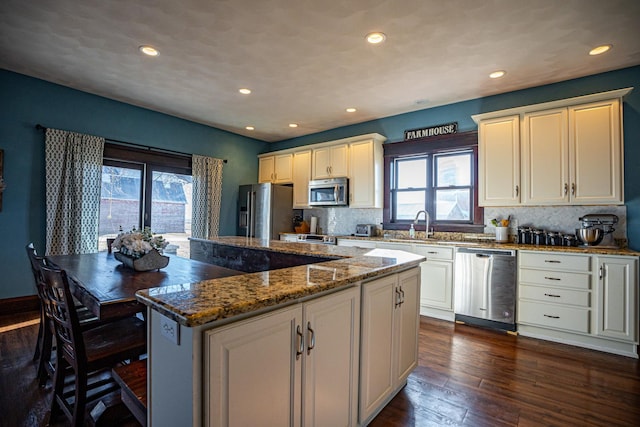 kitchen featuring a kitchen island, appliances with stainless steel finishes, dark hardwood / wood-style floors, and dark stone counters