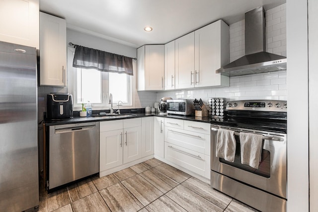 kitchen featuring sink, wall chimney exhaust hood, stainless steel appliances, tasteful backsplash, and white cabinets