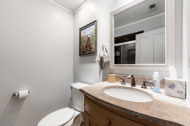 bathroom featuring vanity, toilet, and ornamental molding