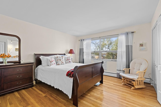 bedroom with light wood-type flooring and a baseboard heating unit