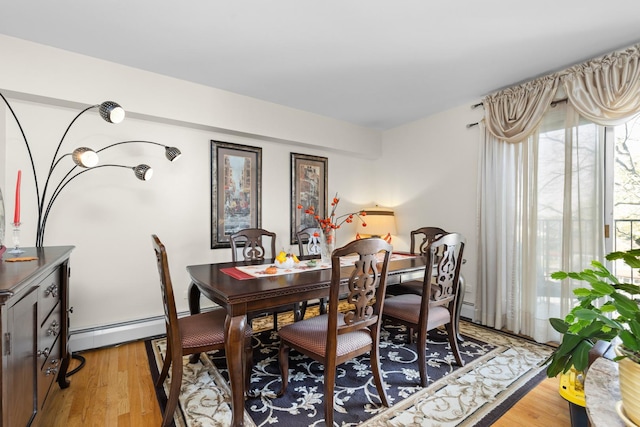 dining space with baseboard heating and light hardwood / wood-style flooring