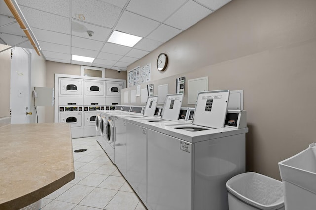 laundry room with washer and clothes dryer, stacked washer and dryer, light tile patterned floors, and sink