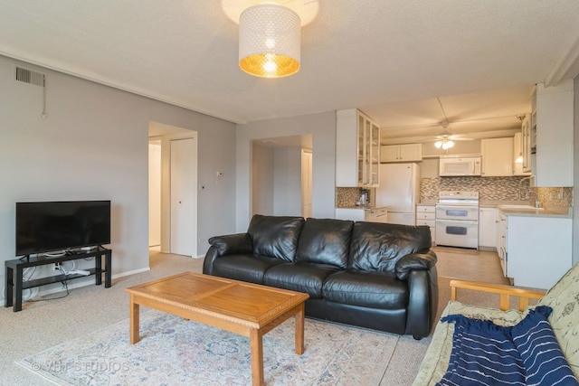 living room featuring a textured ceiling, ceiling fan, and sink