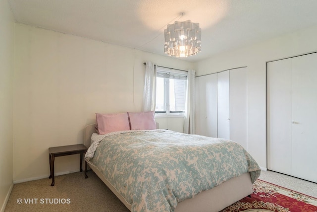 carpeted bedroom featuring two closets and an inviting chandelier