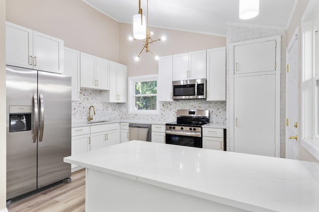 kitchen with pendant lighting, backsplash, white cabinets, sink, and stainless steel appliances