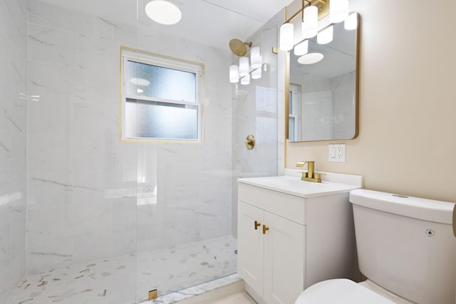 bathroom with tiled shower, vanity, and toilet