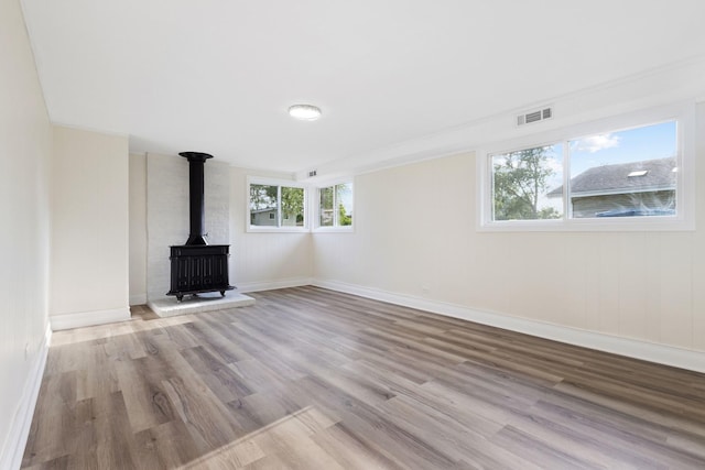 unfurnished living room featuring plenty of natural light, light wood-type flooring, and a wood stove