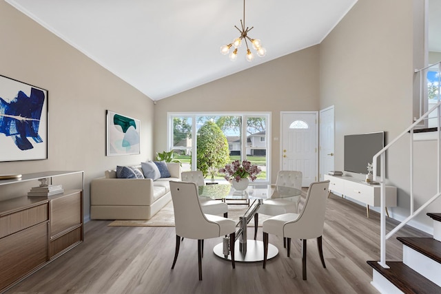 dining area featuring a chandelier, high vaulted ceiling, and light hardwood / wood-style floors