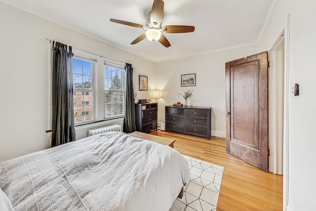 bedroom with radiator, ornamental molding, ceiling fan, and light hardwood / wood-style flooring