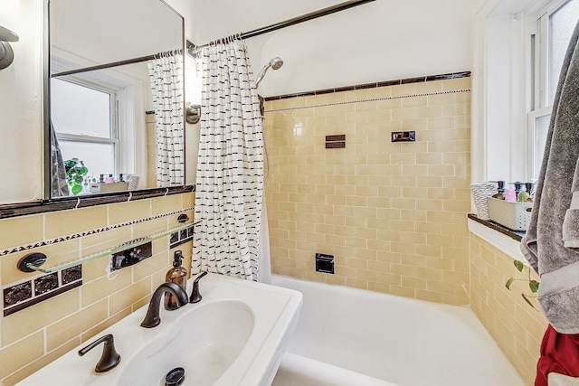 bathroom with shower / bath combo with shower curtain, backsplash, and sink