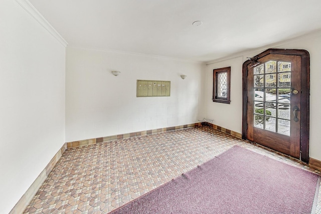 foyer featuring a mail area and crown molding