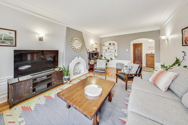 living room with built in shelves, light wood-type flooring, and ornamental molding