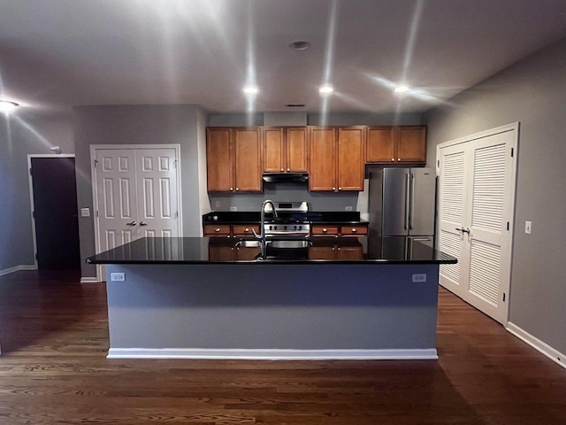 kitchen with sink, a center island with sink, dark hardwood / wood-style floors, and appliances with stainless steel finishes