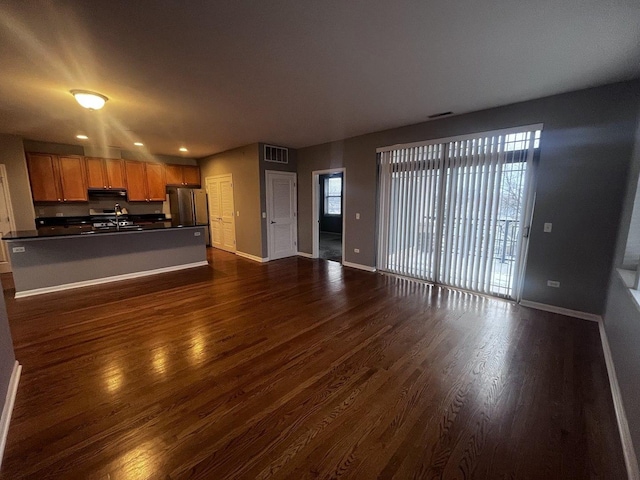 unfurnished living room featuring dark hardwood / wood-style floors, plenty of natural light, and sink