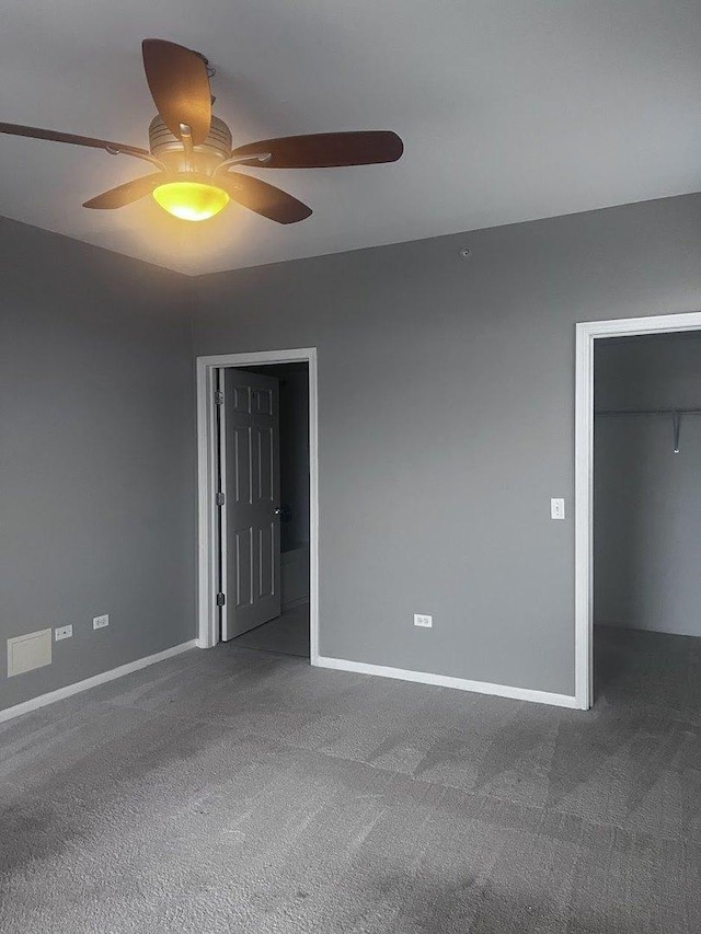 unfurnished bedroom featuring carpet flooring, ceiling fan, a spacious closet, and a closet