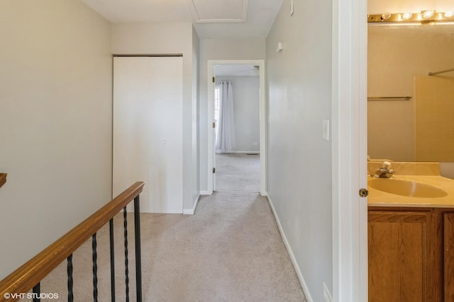 hallway with sink and light colored carpet