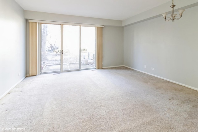 carpeted empty room featuring a chandelier