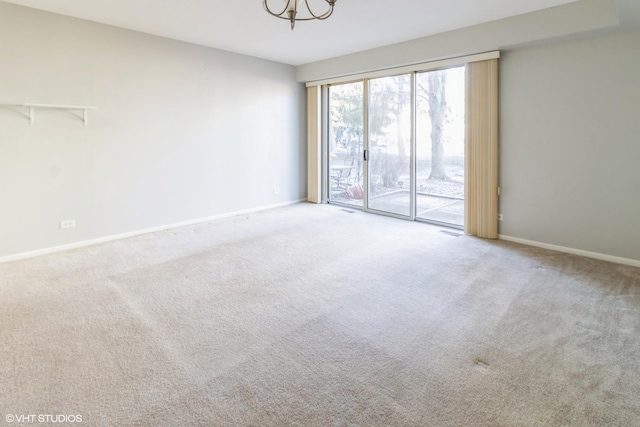 carpeted empty room featuring an inviting chandelier