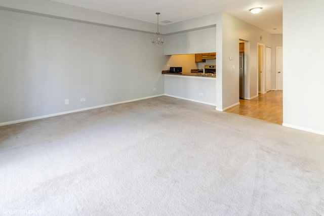 unfurnished living room with light carpet and a notable chandelier