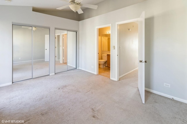 unfurnished bedroom with ensuite bath, light colored carpet, vaulted ceiling, ceiling fan, and multiple closets