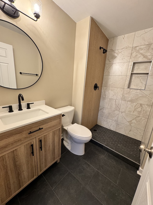 bathroom featuring a tile shower, vanity, and toilet