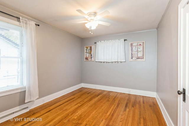 empty room with a healthy amount of sunlight, ceiling fan, wood-type flooring, and ornamental molding