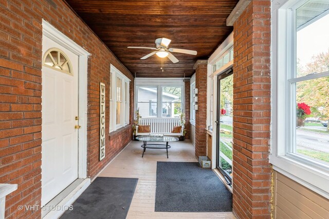 unfurnished sunroom with a healthy amount of sunlight, ceiling fan, and wood ceiling