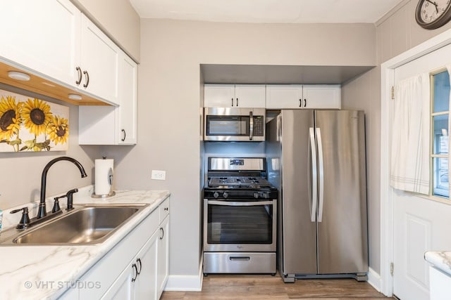 kitchen featuring white cabinetry, sink, light stone counters, and appliances with stainless steel finishes