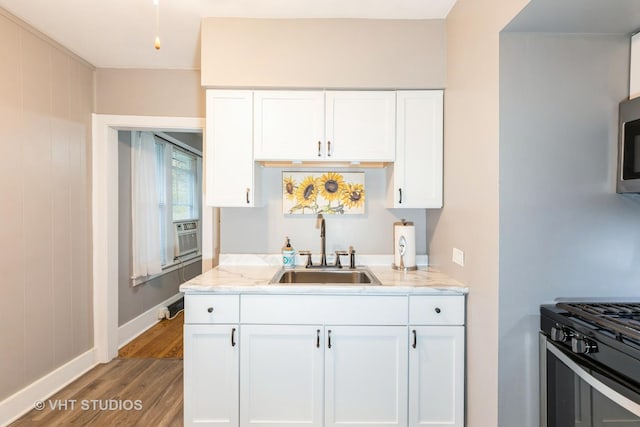 kitchen with light stone countertops, sink, stainless steel appliances, hardwood / wood-style floors, and white cabinets