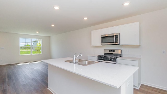 kitchen featuring stainless steel appliances, dark wood-type flooring, sink, white cabinets, and an island with sink