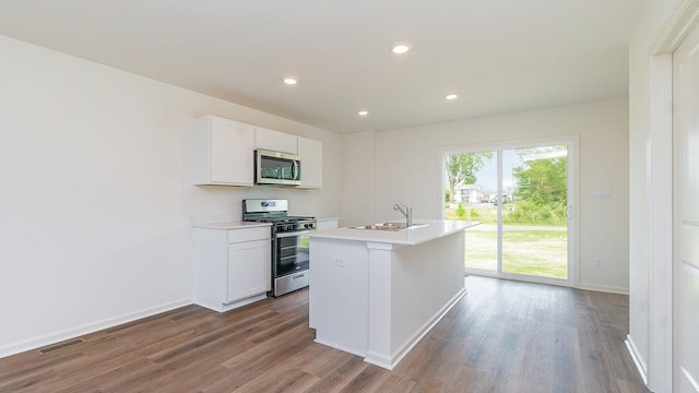 kitchen with white cabinetry, sink, stainless steel appliances, and a center island with sink