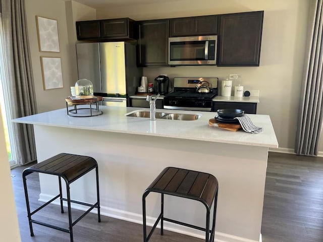 kitchen featuring sink, a kitchen breakfast bar, dark hardwood / wood-style floors, a kitchen island with sink, and appliances with stainless steel finishes