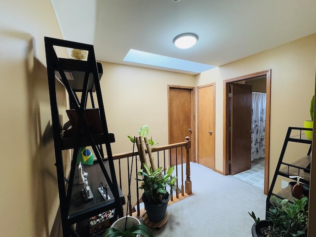 corridor with a skylight and light colored carpet