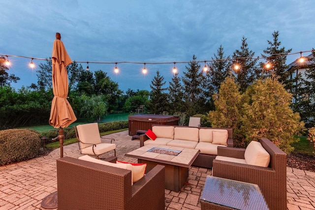 patio terrace at dusk with a hot tub and an outdoor living space with a fire pit