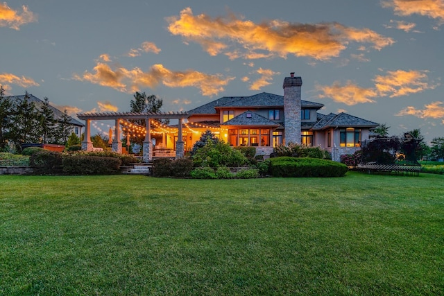 back house at dusk with a pergola and a yard