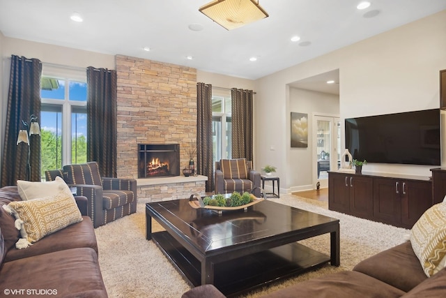 carpeted living room featuring a stone fireplace