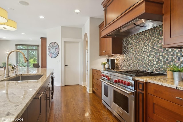 kitchen featuring sink, dark wood-type flooring, light stone counters, double oven range, and custom range hood