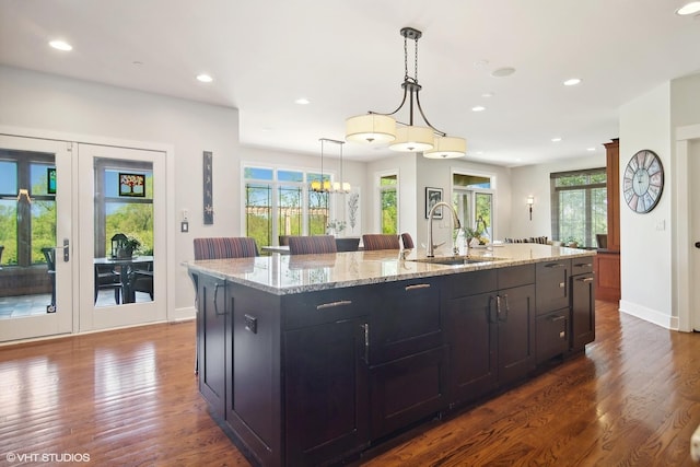 kitchen featuring dark hardwood / wood-style flooring, sink, an island with sink, and decorative light fixtures