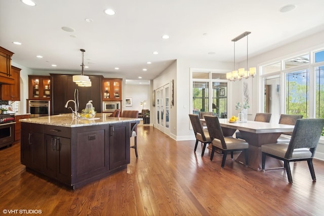 kitchen with a large island, stainless steel appliances, hanging light fixtures, an inviting chandelier, and dark hardwood / wood-style floors