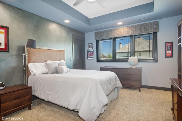 carpeted bedroom with ceiling fan and a tray ceiling