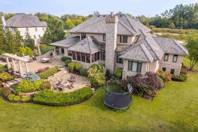 back of house featuring a patio, a trampoline, an outdoor fire pit, and a lawn