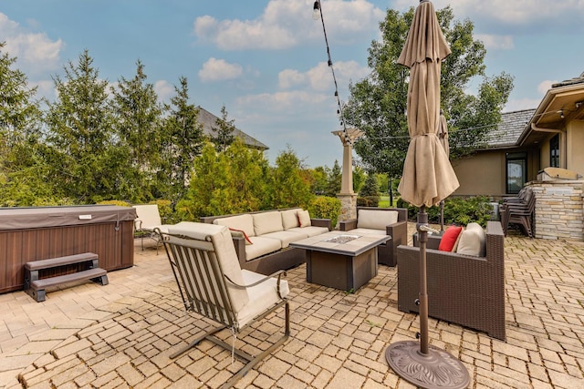 view of patio / terrace with a hot tub and an outdoor living space with a fire pit