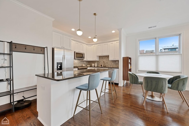 kitchen featuring dark hardwood / wood-style flooring, decorative light fixtures, white cabinets, and appliances with stainless steel finishes