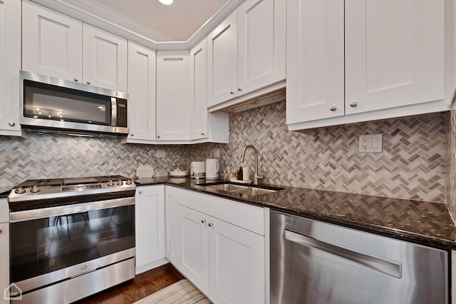 kitchen featuring sink, appliances with stainless steel finishes, dark stone countertops, backsplash, and white cabinets