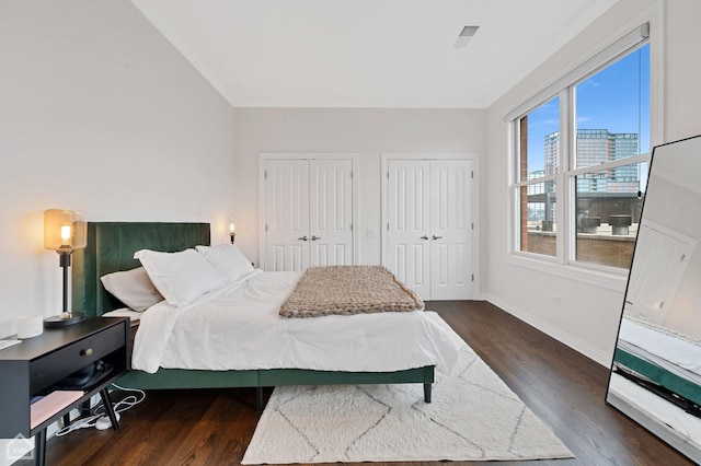 bedroom with two closets and dark wood-type flooring