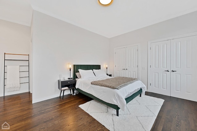 bedroom with multiple closets and dark wood-type flooring