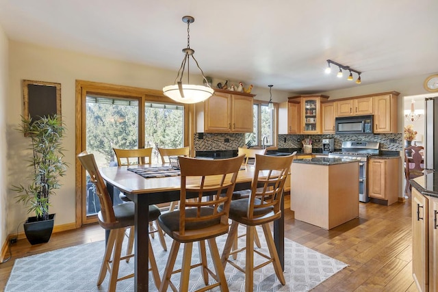 kitchen with light hardwood / wood-style flooring, decorative backsplash, decorative light fixtures, a kitchen island, and stainless steel range oven