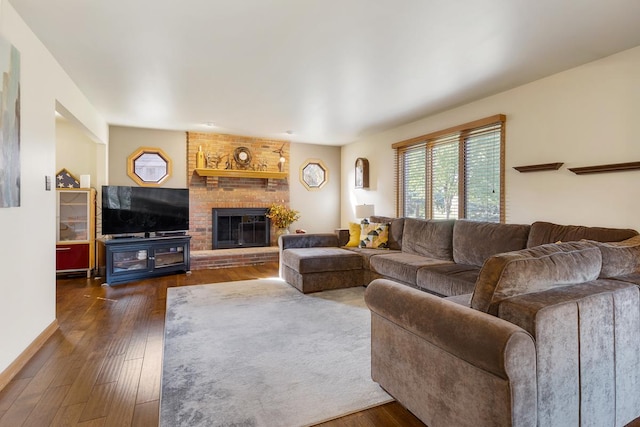 living room with a brick fireplace and dark wood-type flooring